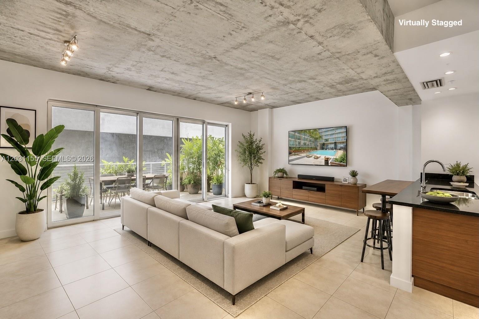 This living room features a concrete ceiling, tile floors, and a sliding glass door balcony — 3449 NE 1st Ave # 109, Miami FL 33137, MIAMI, FL
