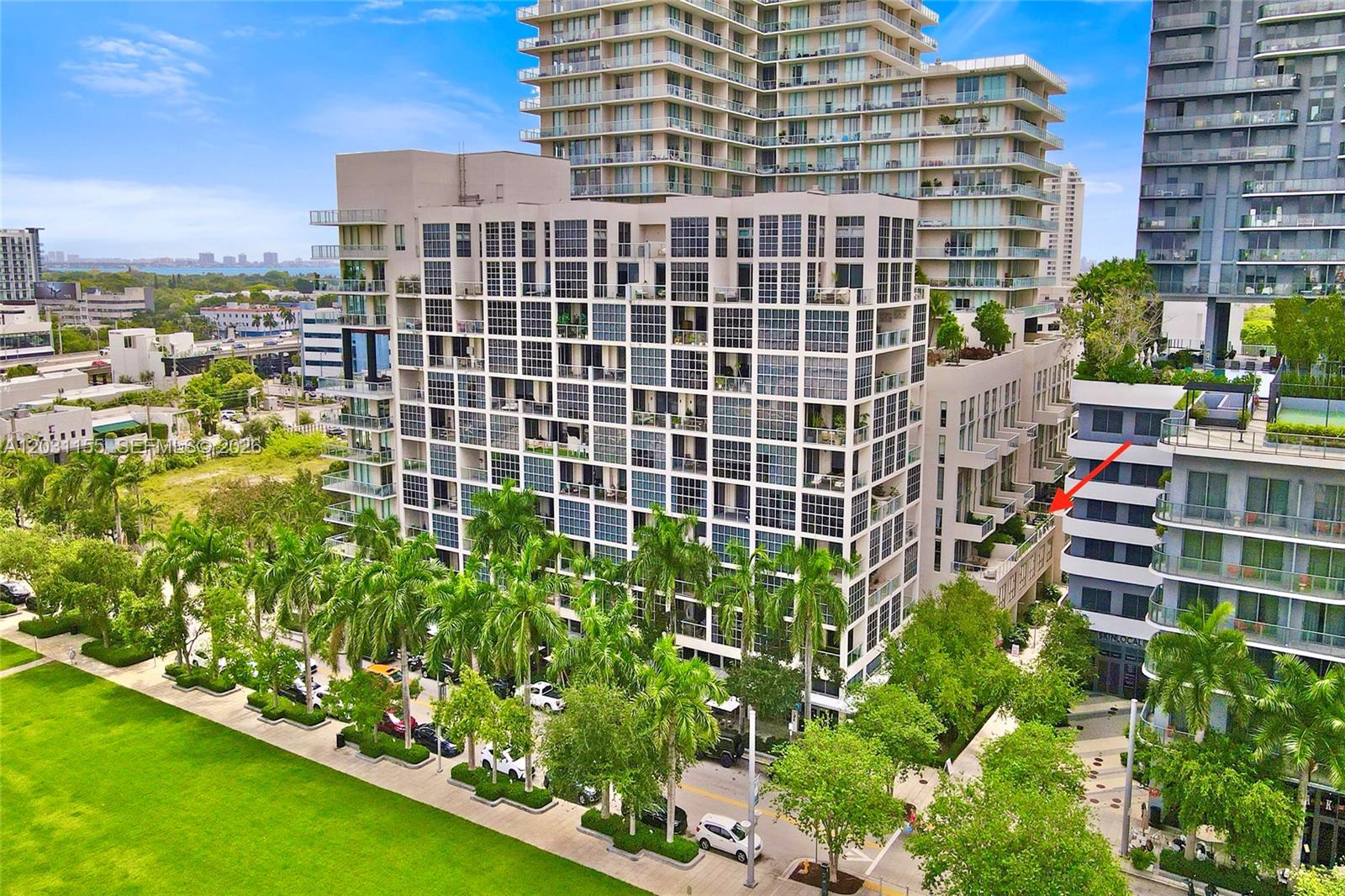 An aerial view shows a modern residential building complex with palm trees and surrounding streets — 3449 NE 1st Ave # 109, Miami FL 33137, MIAMI, FL