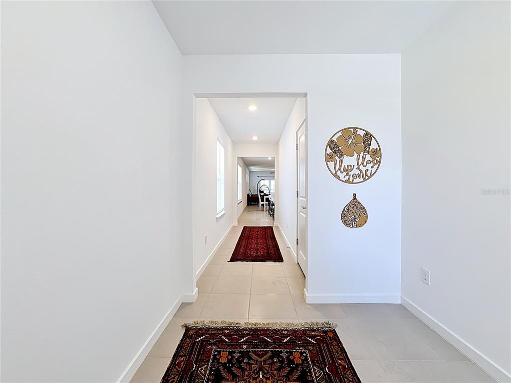A tiled hallway features two patterned area rugs and wall-mounted decorative metal art — 6080 JENSEN VIEW AVENUE, APOLLO BEACH, FL