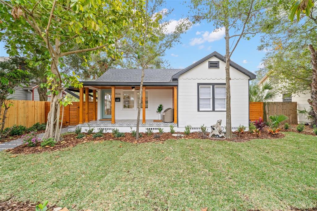 A white single-story house features a covered front porch with wooden posts and tiled flooring — 4536 1ST AVENUE N, ST PETERSBURG, FL