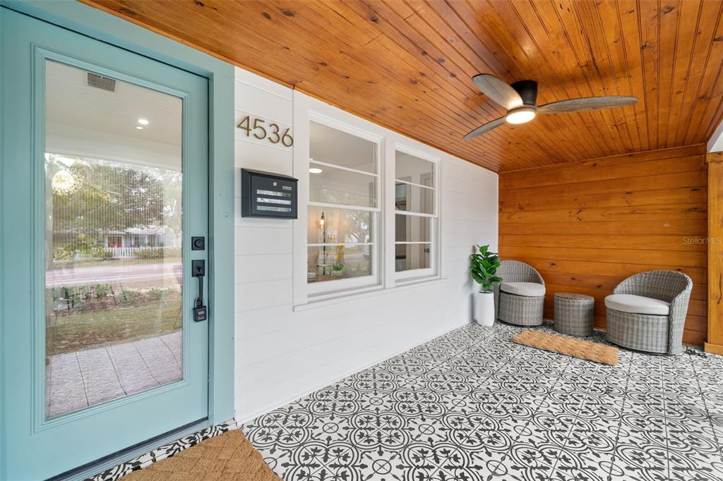 A covered front porch features patterned tile flooring, wood-paneled ceiling, and two wicker chairs — 4536 1ST AVENUE N, ST PETERSBURG, FL