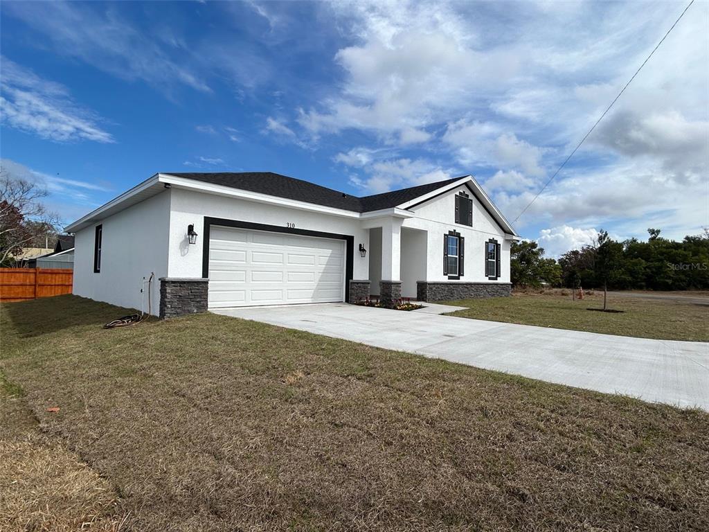 A single-story house with a white exterior, dark roof, and stone accents on the facade — 310 GIBSON AVENUE, LAKE WALES, FL