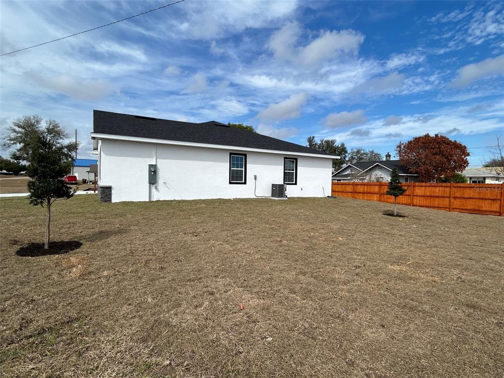The exterior of a white house with a black roof and a wooden fence — 310 GIBSON AVENUE, LAKE WALES, FL