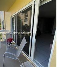 A balcony with a chair and a sliding glass door looking into a room — 7815 N Camino Real # 216, Miami FL 33143, MIAMI, FL