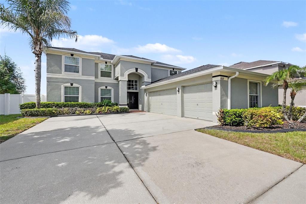 A two-story gray house features a three-car garage and a concrete driveway — 4227 BALINGTON DRIVE, VALRICO, FL