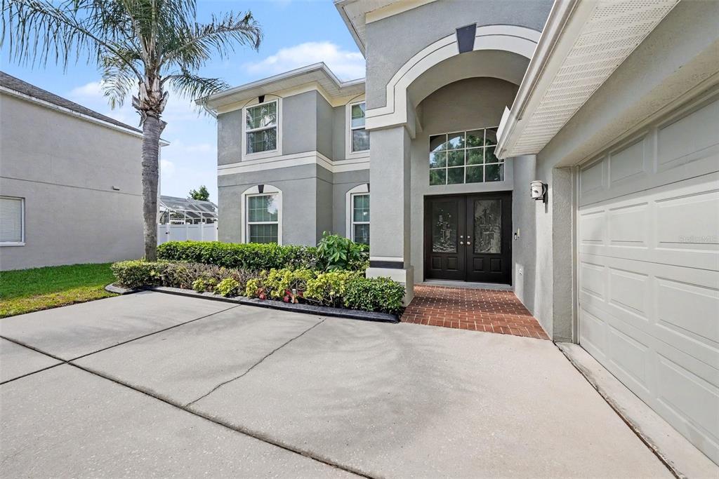 A two-story house with a gray stucco exterior, a palm tree, and a brick entryway — 4227 BALINGTON DRIVE, VALRICO, FL