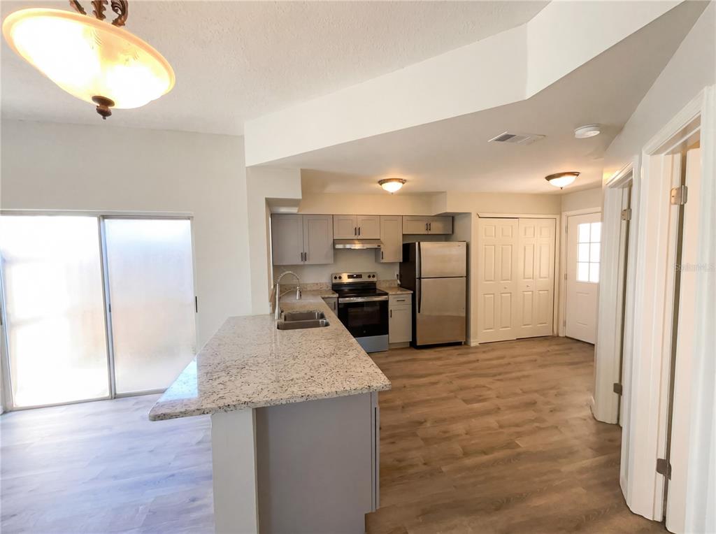A kitchen features light gray cabinets, granite countertops, stainless steel appliances, and wood-look flooring — 780 OLYMPIC CIRCLE UNIT I3, OCOEE, FL