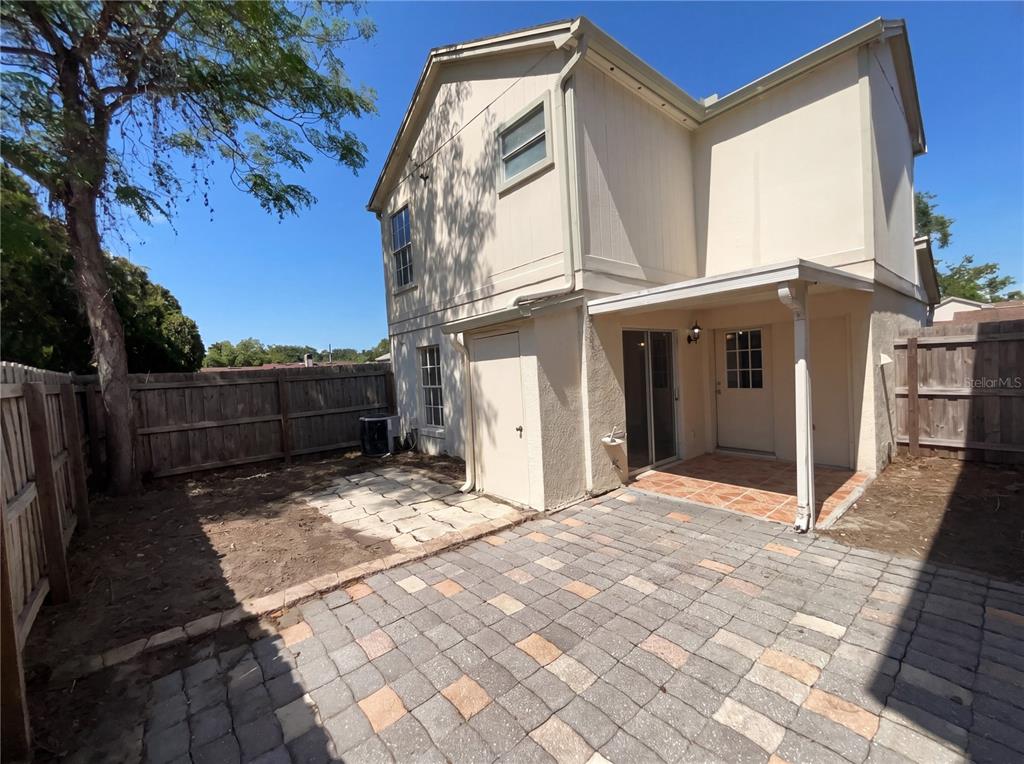 A two-story house exterior features a paved patio, a covered porch, and a fenced yard — 780 OLYMPIC CIRCLE UNIT I3, OCOEE, FL
