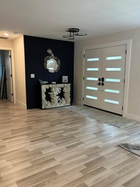 An entryway features light wood-look flooring, a dark slatted accent wall, and double front doors — 101 CHERRY HILL CIRCLE, LONGWOOD, FL