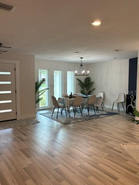 A dining area with a chandelier and table sits in an open-concept room with wood flooring — 101 CHERRY HILL CIRCLE, LONGWOOD, FL