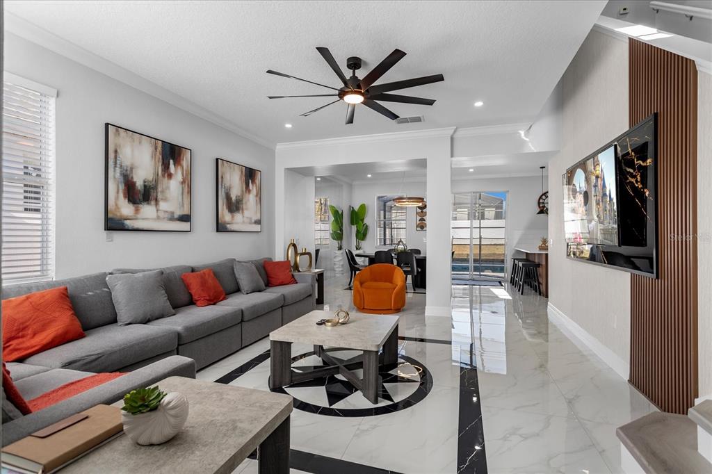 A modern living room features a gray sectional, orange accents, and a large wall-mounted television — 117 FOREST VIEW COURT, DAVENPORT, FL