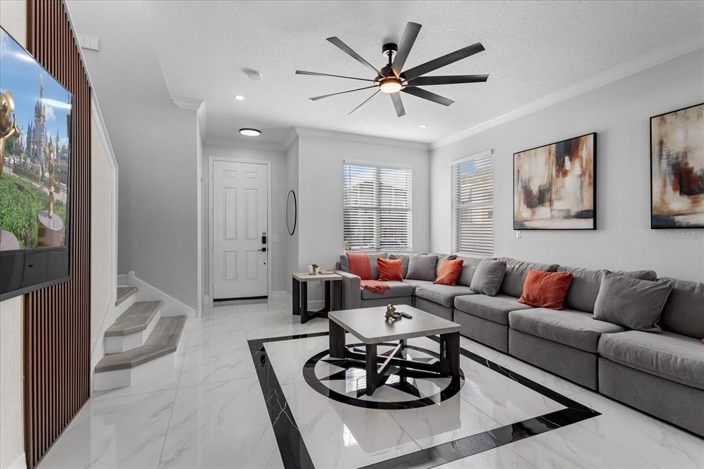 A living room features a grey sectional sofa, a coffee table, and white tile flooring — 117 FOREST VIEW COURT, DAVENPORT, FL
