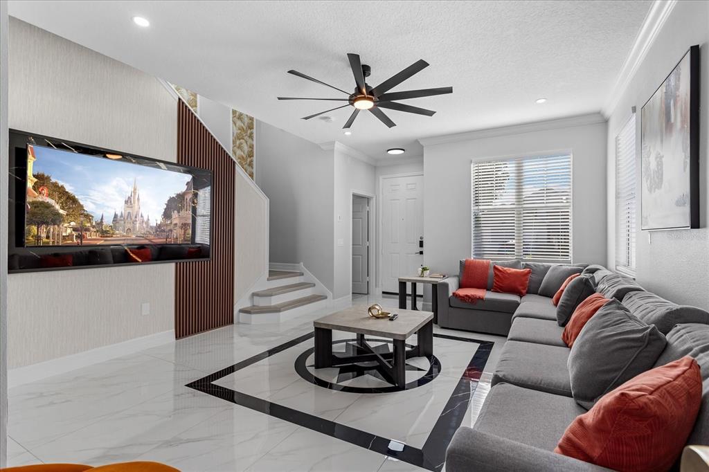 A modern living room features a large sectional sofa, a wall-mounted television, and tiled flooring — 117 FOREST VIEW COURT, DAVENPORT, FL