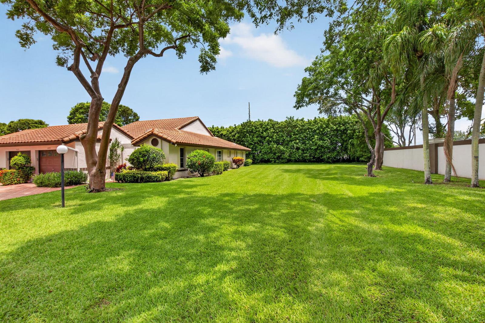 A single-story house with a tiled roof sits beside a large, manicured green lawn — 6082 Waldwick Circle, Delray Beach FL 33484, DELRAY BEACH, FL