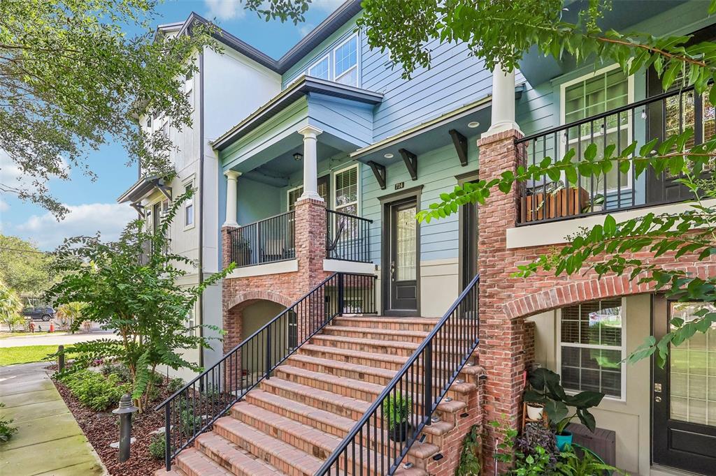 A multi-story building exterior features a brick staircase leading to a raised porch and entrance — 714 CATALONIA COVE, OVIEDO, FL