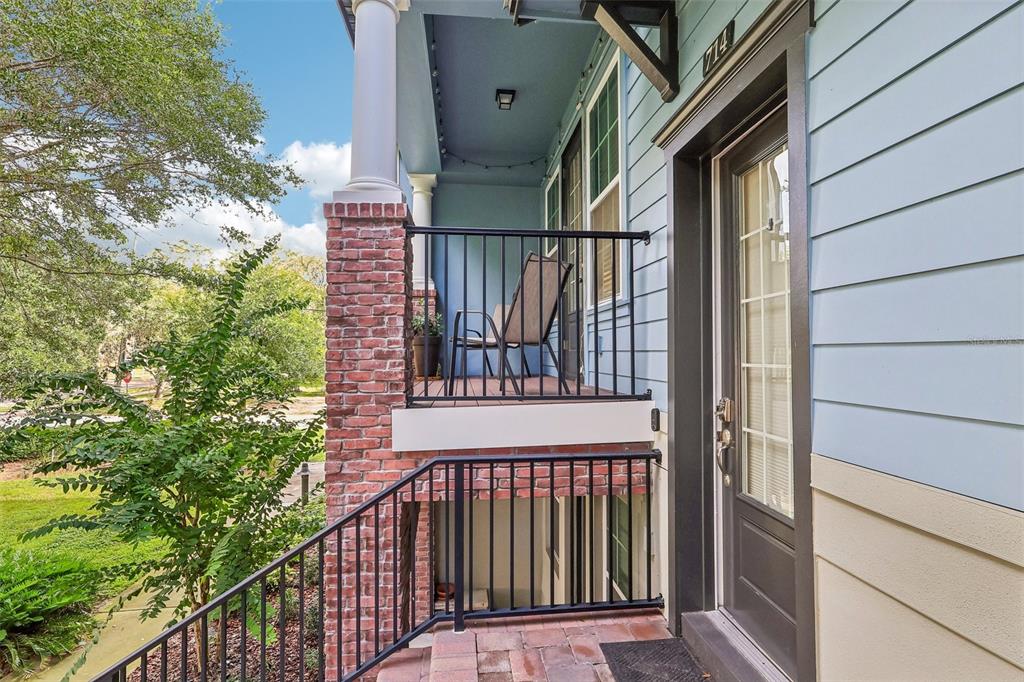 A blue-sided house features a brick-based porch with black railings and a glass-paneled door — 714 CATALONIA COVE, OVIEDO, FL
