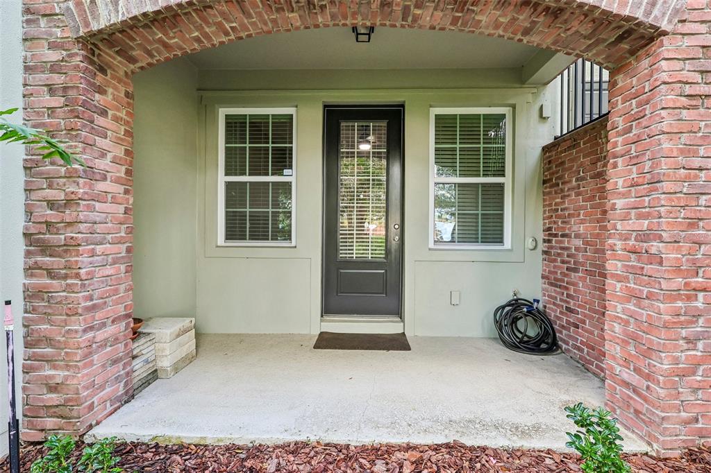 A covered brick-arched porch features a dark front door flanked by two windows — 714 CATALONIA COVE, OVIEDO, FL