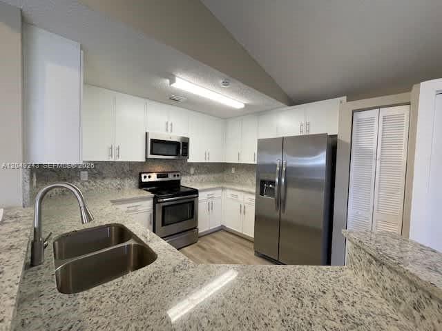 A kitchen features white cabinets, granite countertops, stainless steel appliances, and a double-basin sink — MIAMI, FL