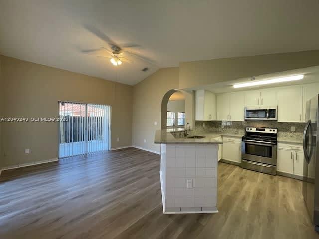 An open-concept kitchen with white cabinets and a breakfast bar overlooks a living area — MIAMI, FL