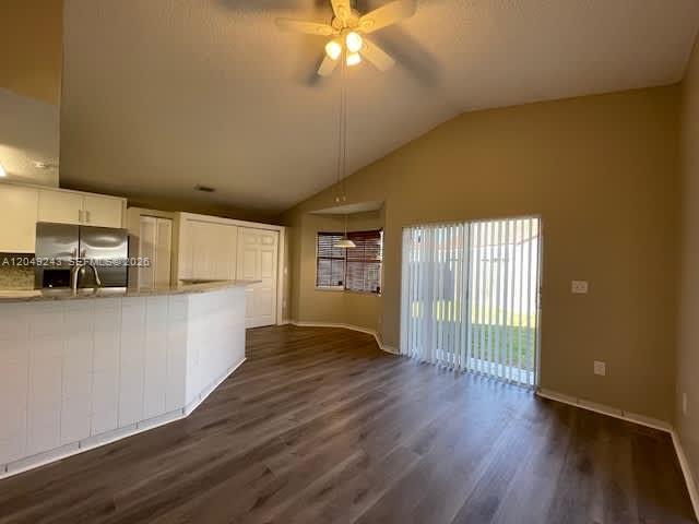 An open-concept kitchen with a breakfast bar overlooks a living area with wood-look flooring — MIAMI, FL