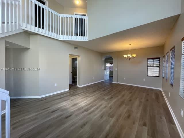 An open living area features light wood-look flooring, a high ceiling, and a white balcony railing — MIAMI, FL