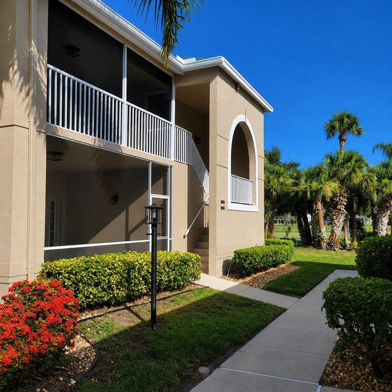 A two-story building features a screened-in balcony, an arched entryway, and a concrete walkway — 9560 HIGH GATE DRIVE UNIT 1626, SARASOTA, FL