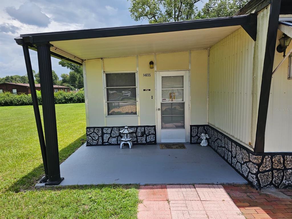 A covered porch with a stone-patterned base leads to the front door of a home — 14655 SE 47TH COURT, SUMMERFIELD, FL