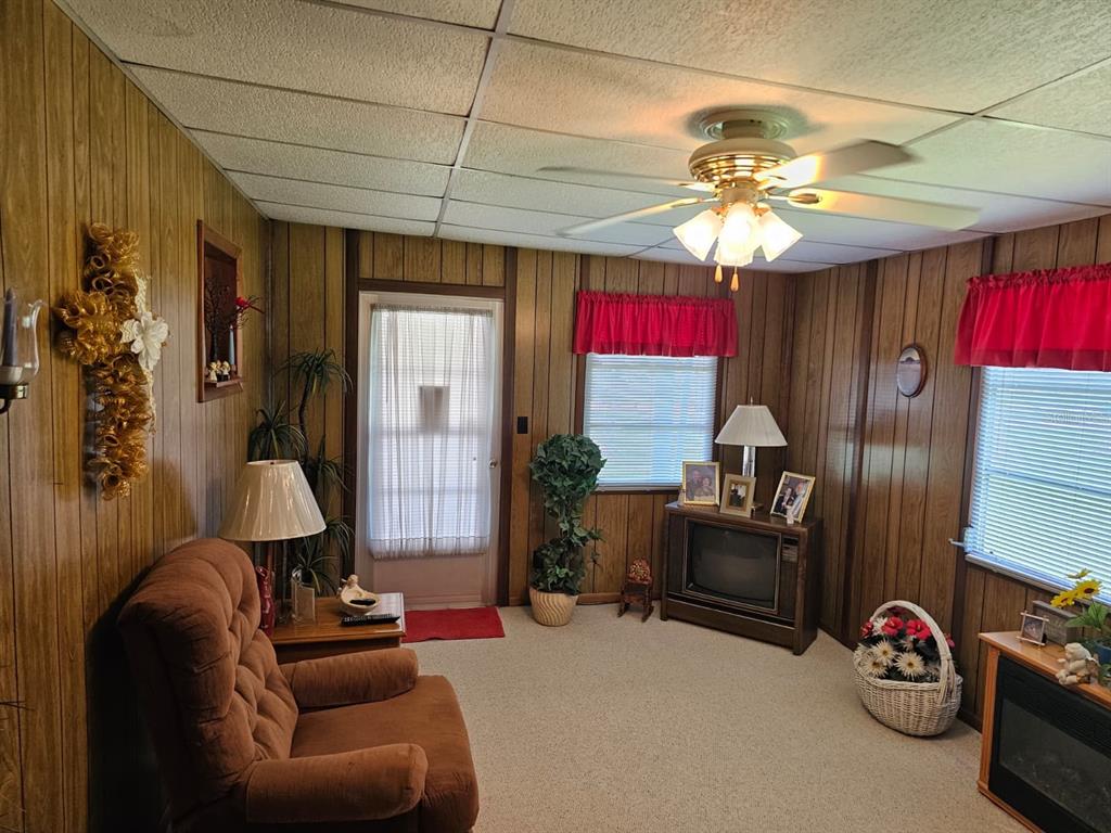 A living room features wood-paneled walls, a ceiling fan, a recliner, and a television console — 14655 SE 47TH COURT, SUMMERFIELD, FL