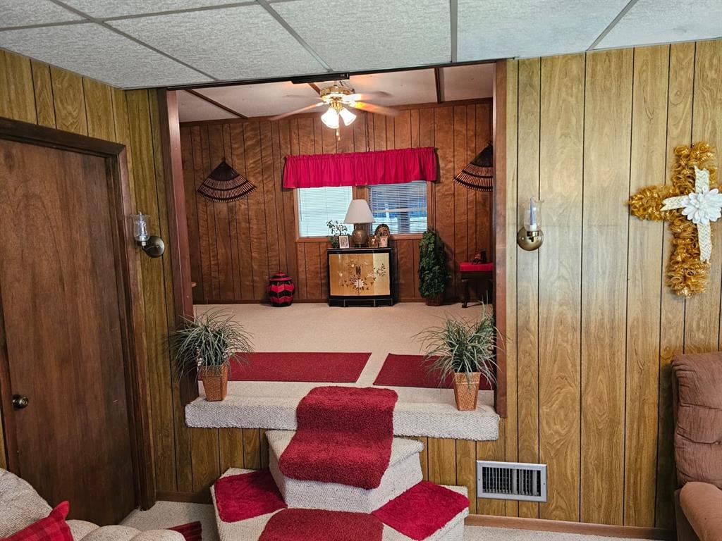 A sunken living room features wood-paneled walls, carpeted steps, and a ceiling fan — 14655 SE 47TH COURT, SUMMERFIELD, FL