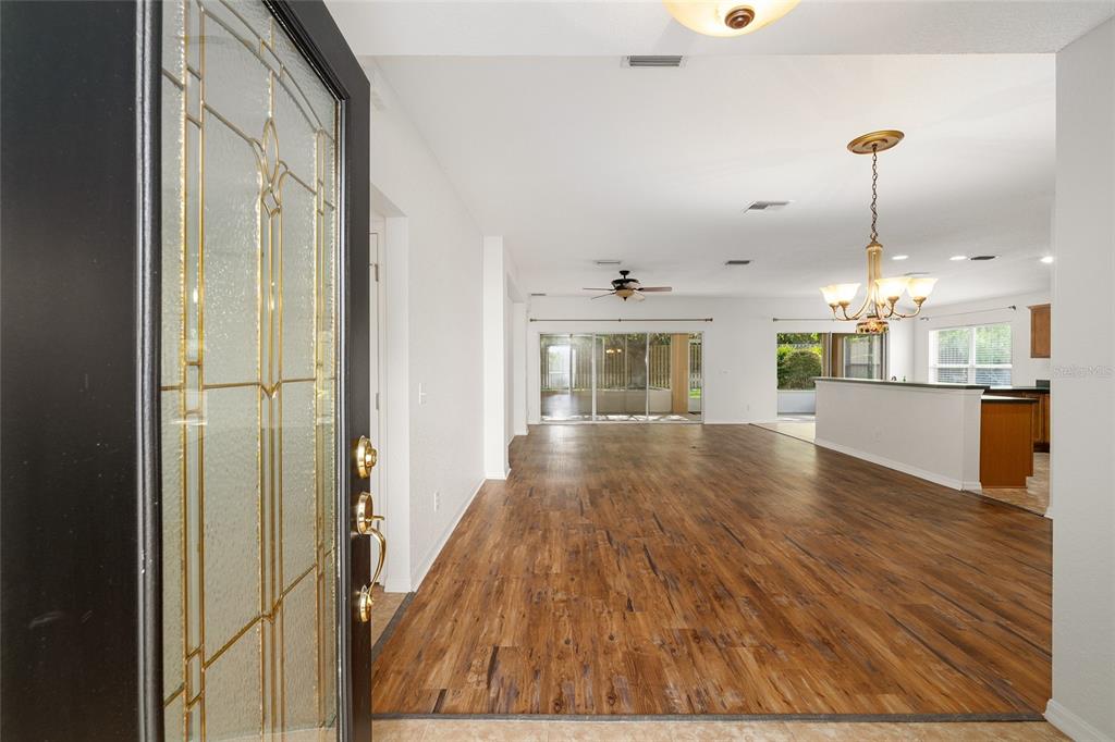 An entryway opens into a spacious living area with wood-look flooring and a kitchen island — 13358 SE 86TH CIRCLE, SUMMERFIELD, FL