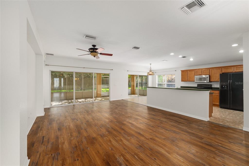 An open-concept living area features wood-look flooring, a kitchen with dark appliances, and sliding doors — 13358 SE 86TH CIRCLE, SUMMERFIELD, FL