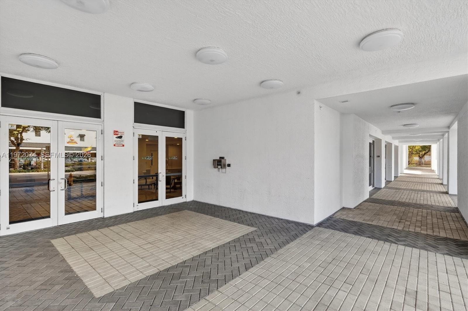 A covered exterior walkway features white walls, recessed ceiling lights, and a paved brick floor — 900 SW 8th St # 505, Miami FL 33130, MIAMI, FL