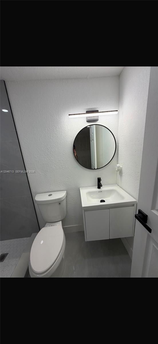 A modern bathroom features a floating vanity, a round mirror, and a white toilet — 14321 Madison St # 1, Miami FL 33176, MIAMI, FL