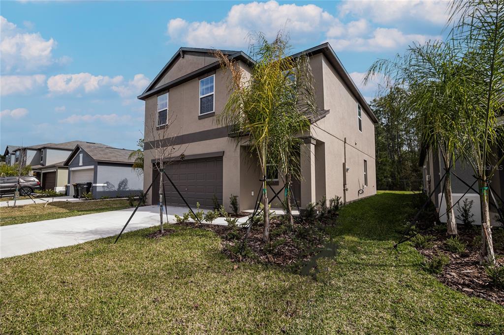 A two-story tan house with a two-car garage and palm trees in the front yard — 2189 TENEROC TRAIL, LAKELAND, FL