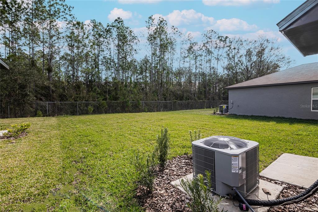 A backyard features a grassy lawn, a chain-link fence, and an air conditioning unit — 2189 TENEROC TRAIL, LAKELAND, FL