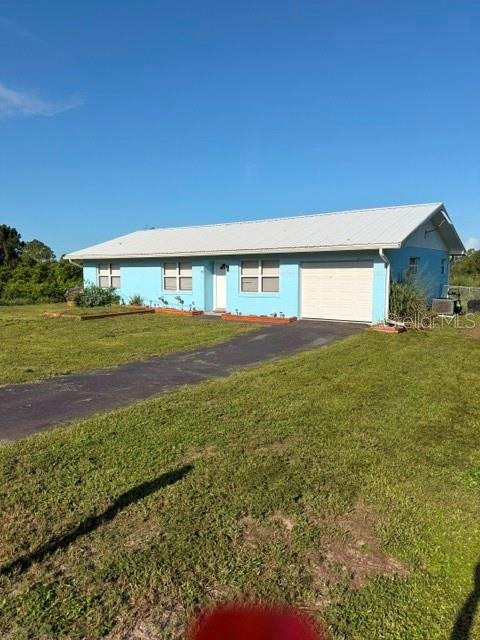 A light blue, single-story house with a white metal roof and an attached garage — 113 WHITE AVENUE NE, LAKE PLACID, FL