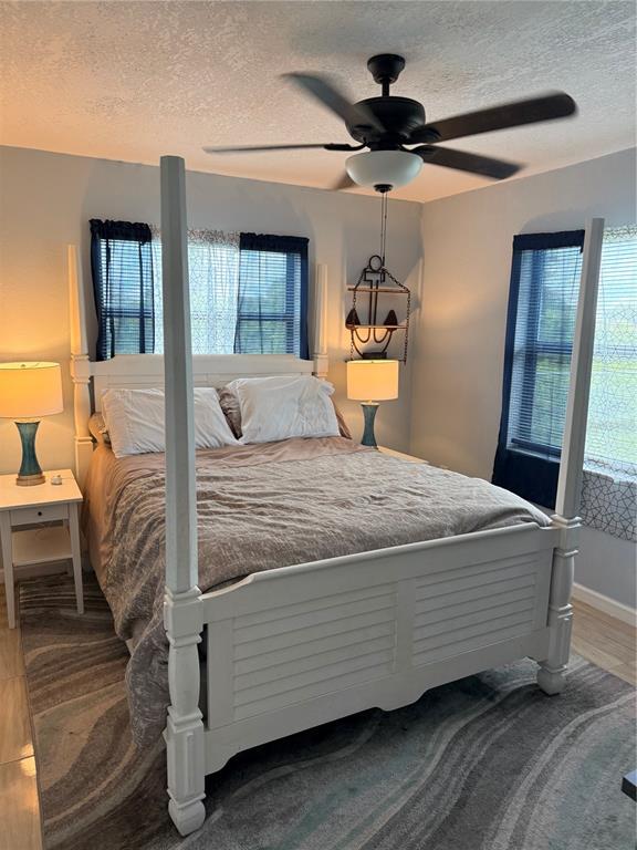 A bedroom features a white four-poster bed, two nightstands with lamps, and a ceiling fan — 113 WHITE AVENUE NE, LAKE PLACID, FL