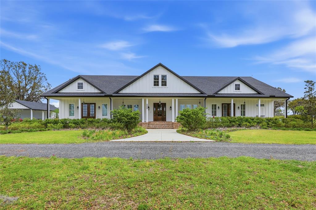 A white farmhouse with a dark roof and a covered front porch sits on grass — 11131 NE 35TH STREET, BRONSON, FL
