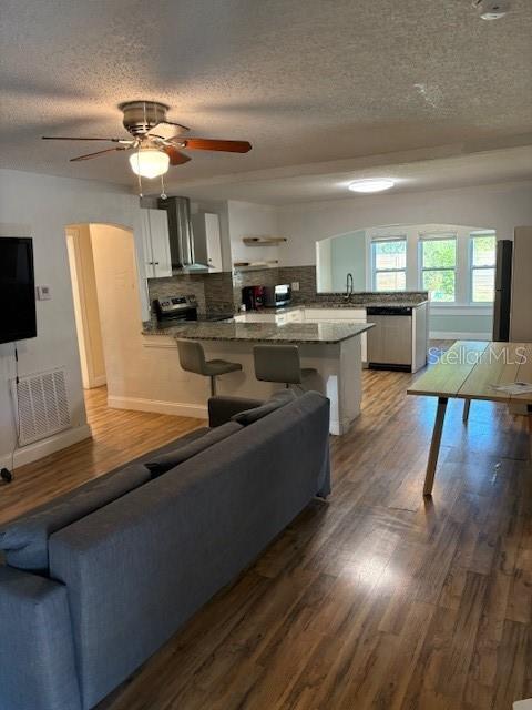 An open-concept living room and kitchen featuring wood-look flooring, a ceiling fan, and bar seating — 4035 14TH AVENUE S, ST PETERSBURG, FL