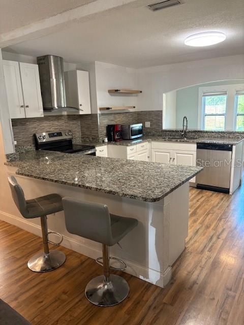 A kitchen features a granite breakfast bar, stainless steel appliances, and wood-look flooring — 4035 14TH AVENUE S, ST PETERSBURG, FL