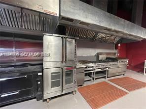 A commercial kitchen featuring stainless steel ovens, a range, and overhead ventilation hoods — 2739 NW 54th St, Miami FL 33142, MIAMI, FL