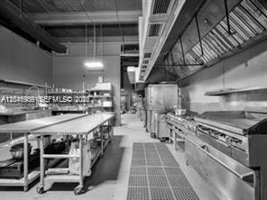 A commercial kitchen features stainless steel prep tables, cooking equipment, and a large ventilation hood — 2739 NW 54th St, Miami FL 33142, MIAMI, FL