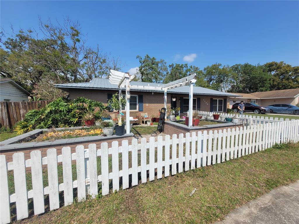 A single-story brick house features a white picket fence, a pergola, and a front garden — 5203 PRESIDENTIAL STREET, SEFFNER, FL