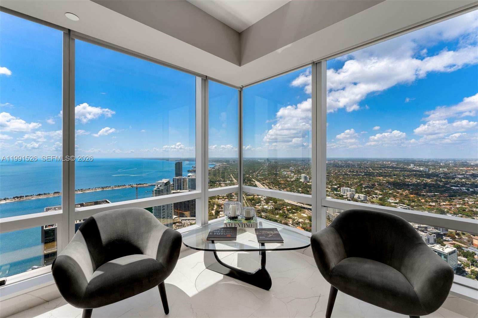 A corner room features floor-to-ceiling windows, two gray armchairs, and a glass coffee table — 1425 Brickell Ave, Miami FL 33131, MIAMI, FL
