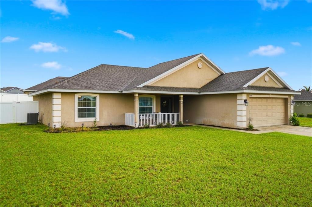 A single-story house with a tan stucco exterior, a two-car garage, and a front porch — 1593 LEMON AVENUE, WINTER HAVEN, FL