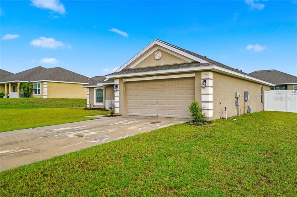 A tan, single-story suburban house with a two-car garage and a concrete driveway — 1593 LEMON AVENUE, WINTER HAVEN, FL