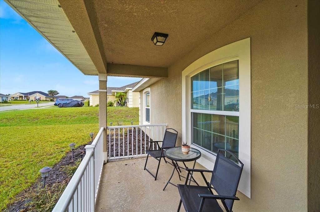 A covered front porch features a small table and two chairs overlooking a grassy lawn — 1593 LEMON AVENUE, WINTER HAVEN, FL