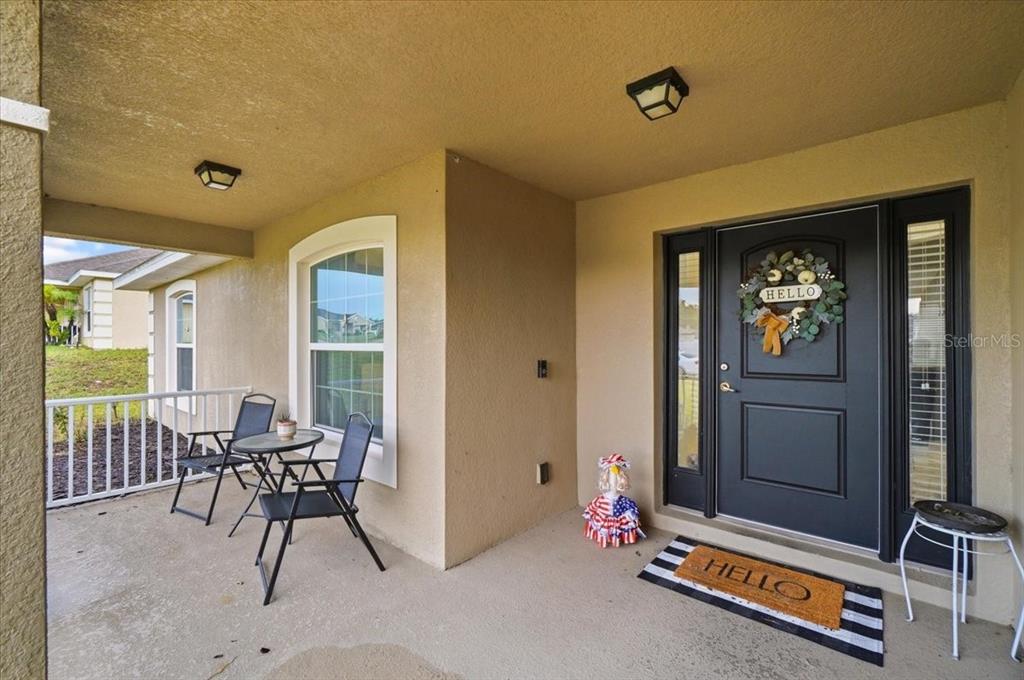 A covered front porch features a dark door, two chairs with a table, and a doormat — 1593 LEMON AVENUE, WINTER HAVEN, FL