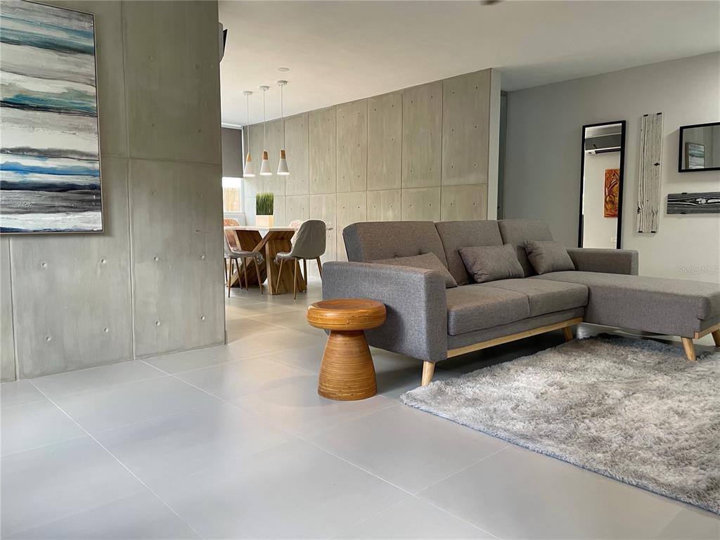 A living room with a gray sectional sofa, a wooden side table, and concrete walls — 290 SANTA ANA AVENUE, GUAYNABO, PR
