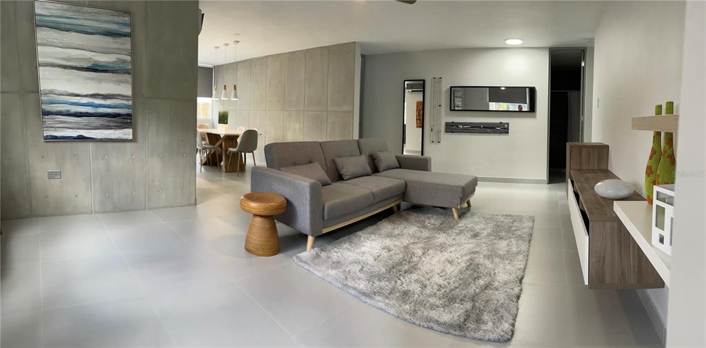 A modern living room features a gray sectional sofa, a shag rug, and concrete walls — 290 SANTA ANA AVENUE, GUAYNABO, PR
